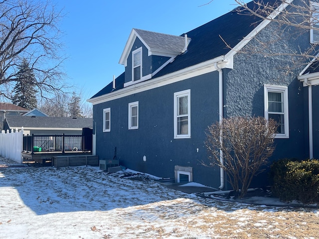 view of snow covered exterior featuring a deck and stucco siding