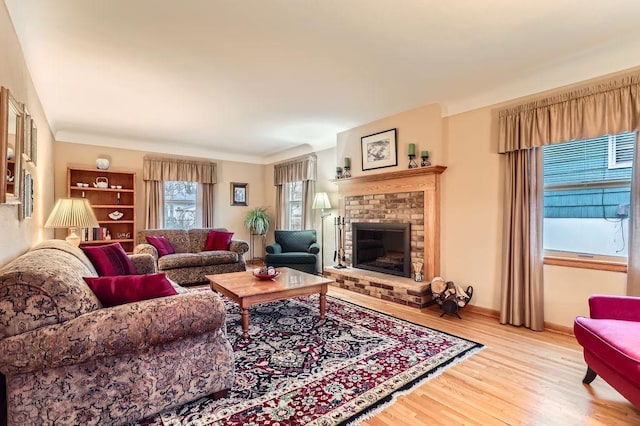 living area with a fireplace, light wood-style flooring, and baseboards