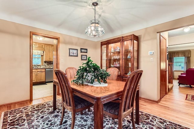 dining area featuring light wood finished floors, baseboards, a chandelier, and a wealth of natural light