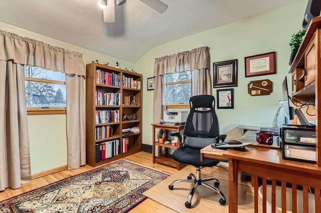 office space featuring lofted ceiling, light wood finished floors, a ceiling fan, and baseboards