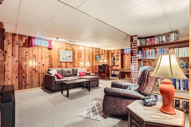 living room featuring a paneled ceiling, carpet, and wooden walls