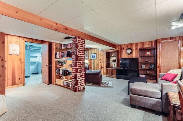 living area featuring carpet, wooden walls, and baseboards