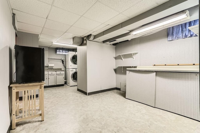 laundry area with stacked washing maching and dryer, baseboards, light floors, and cabinet space