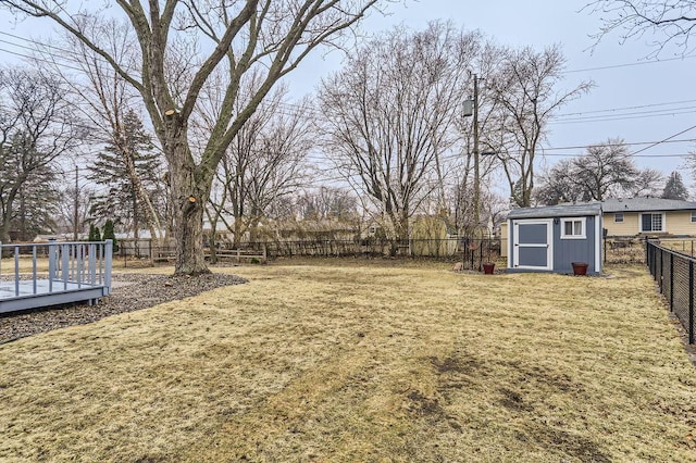 view of yard with an outbuilding, a fenced backyard, a wooden deck, and a storage shed