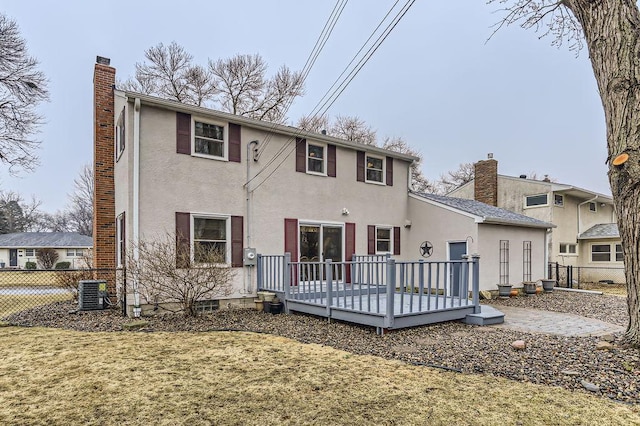 back of property featuring a chimney, fence, cooling unit, a wooden deck, and stucco siding