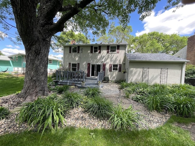 rear view of house with fence, a chimney, a wooden deck, and stucco siding