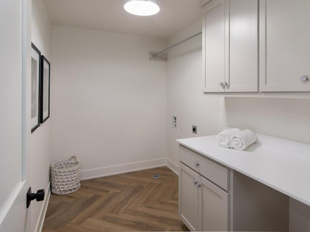 clothes washing area featuring cabinet space, electric dryer hookup, and baseboards