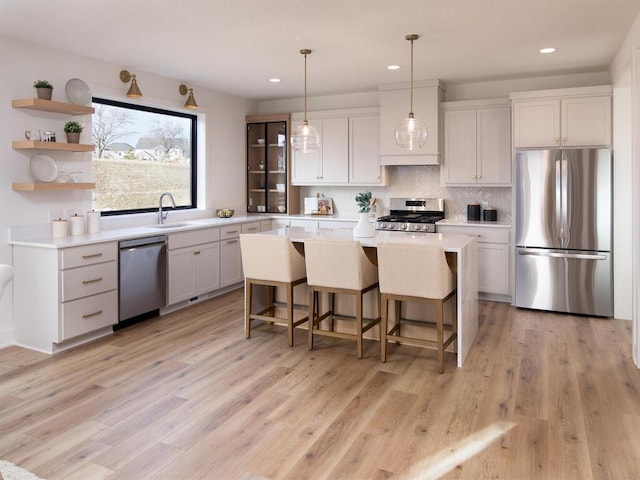 kitchen featuring a breakfast bar, stainless steel appliances, a sink, and light countertops