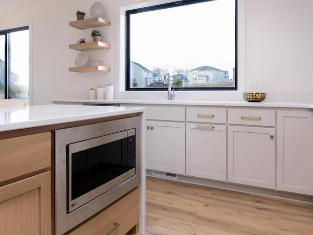 kitchen featuring light countertops, stainless steel microwave, and light wood-type flooring