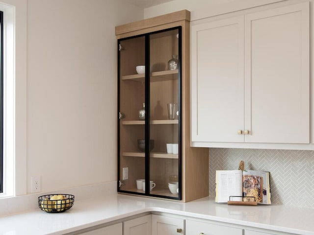 interior space featuring light countertops, backsplash, and white cabinetry