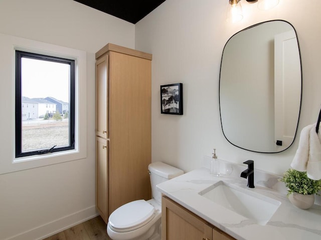 bathroom with toilet, baseboards, wood finished floors, and vanity