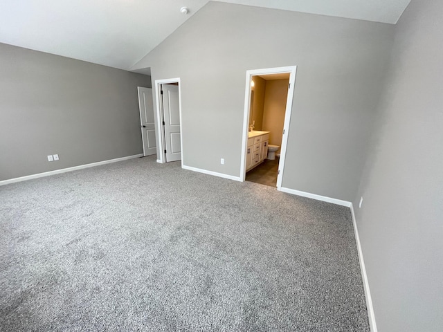 unfurnished bedroom with lofted ceiling, carpet, connected bathroom, and baseboards