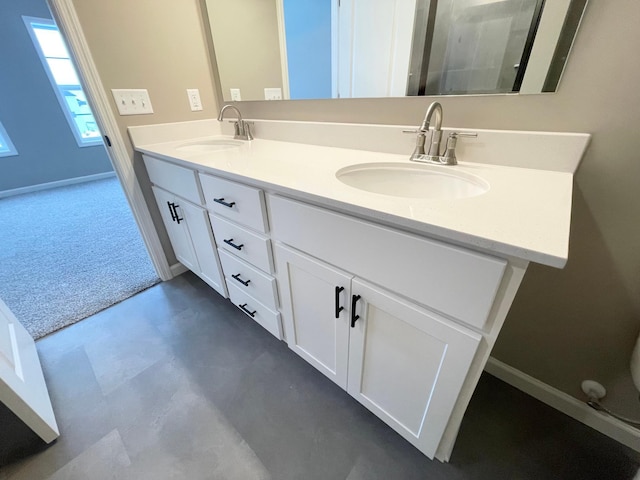 full bathroom with double vanity, a sink, and baseboards