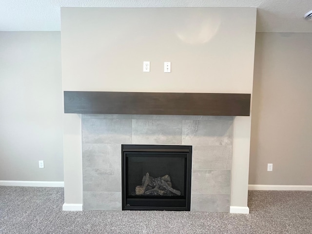 details featuring a textured ceiling, a tiled fireplace, carpet flooring, and baseboards