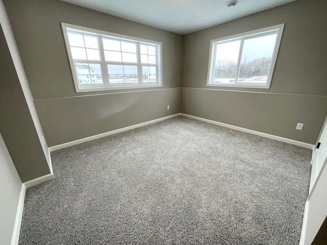 spare room featuring carpet and baseboards