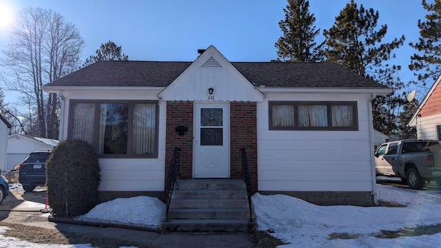 bungalow-style home with entry steps and a shingled roof