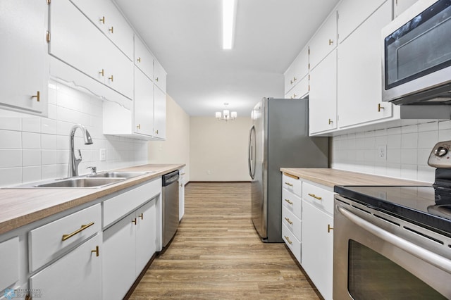 kitchen featuring wood finished floors, a sink, light countertops, white cabinets, and appliances with stainless steel finishes