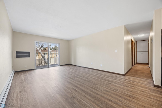 empty room with wood finished floors, baseboards, and a baseboard radiator