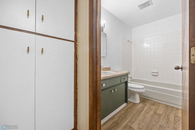 full bathroom featuring vanity, wood finished floors, visible vents, shower / tub combination, and toilet