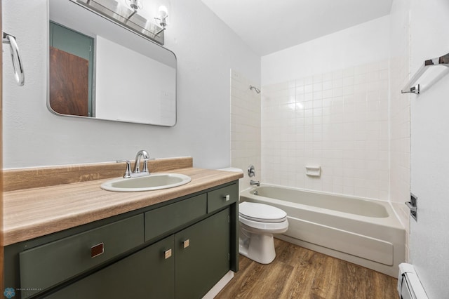 bathroom featuring shower / washtub combination, toilet, baseboard heating, wood finished floors, and vanity