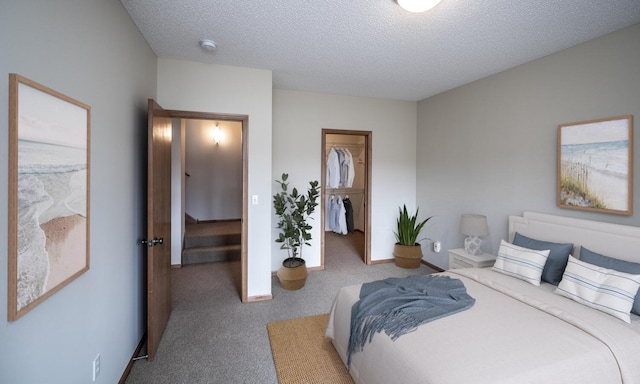 carpeted bedroom featuring a closet, a spacious closet, baseboards, and a textured ceiling