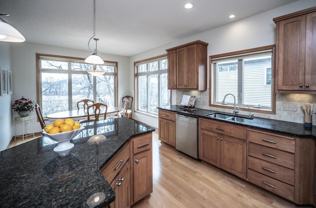 kitchen featuring dishwashing machine, a sink, light wood-style floors, hanging light fixtures, and backsplash