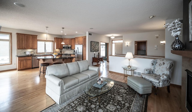 living room featuring light wood-type flooring, a fireplace, visible vents, and baseboards