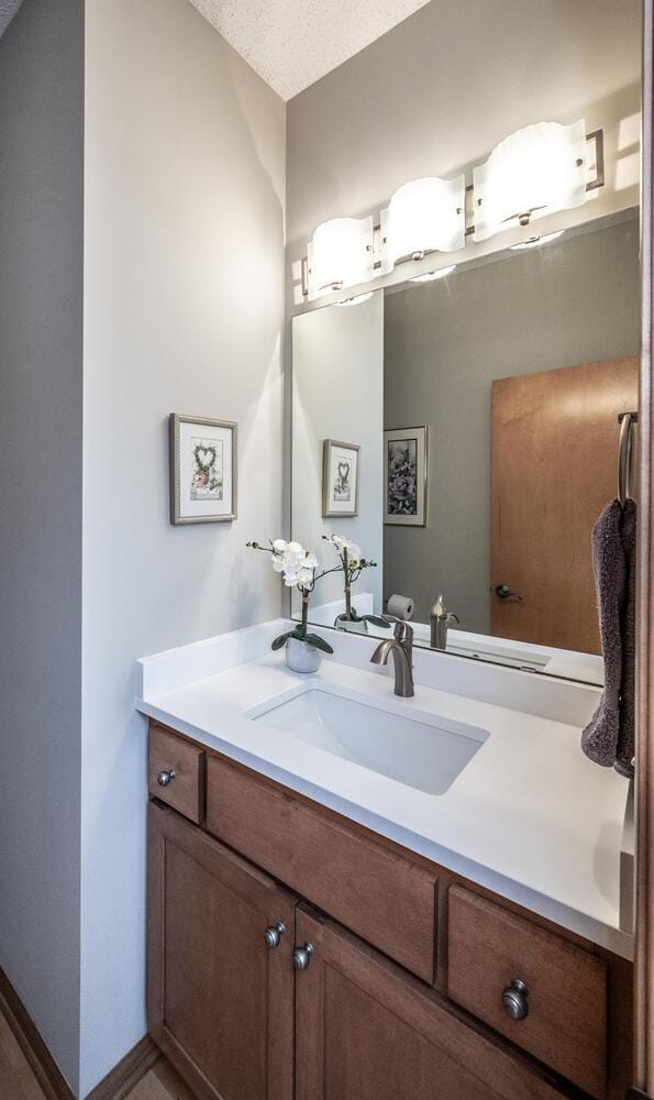 bathroom with a textured ceiling, vanity, and baseboards