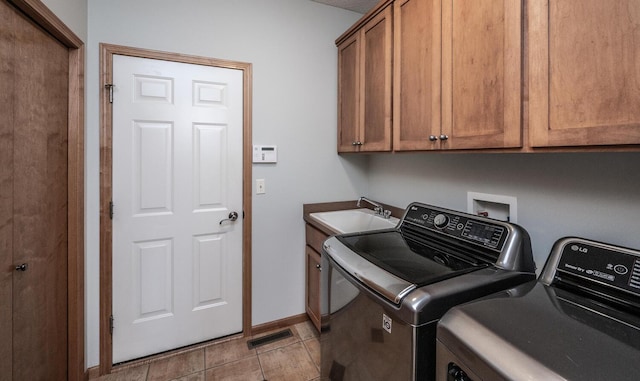 laundry area featuring washing machine and clothes dryer, light tile patterned floors, cabinet space, a sink, and baseboards