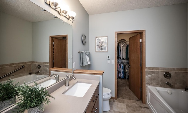 full bath with toilet, vanity, a textured ceiling, and a bath