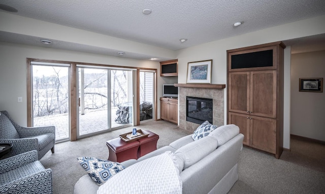 living room with light carpet, baseboards, a textured ceiling, and a tile fireplace