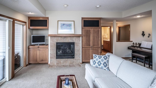 living room featuring a tile fireplace, light colored carpet, and a textured ceiling