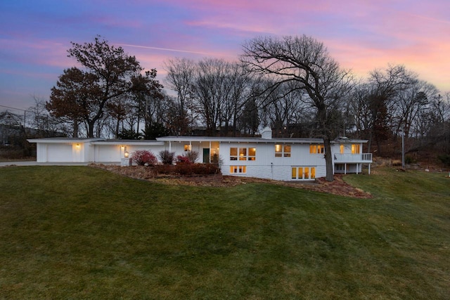 view of front of house featuring a garage, a yard, a chimney, and driveway