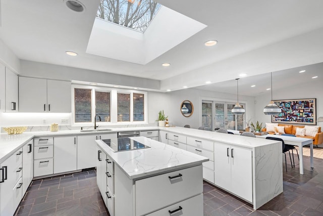 kitchen featuring a kitchen island, a peninsula, light stone countertops, a sink, and recessed lighting