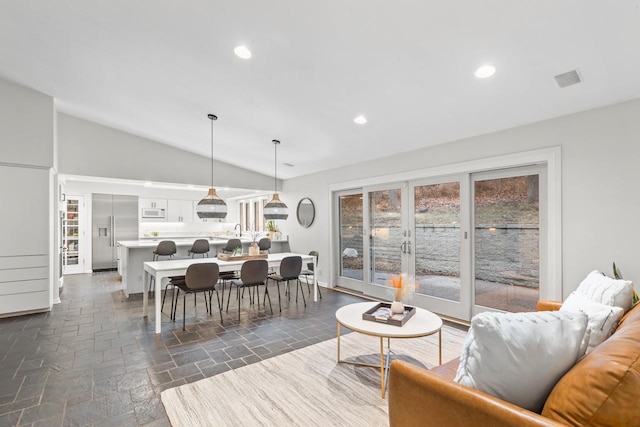 living room featuring lofted ceiling, recessed lighting, stone tile flooring, and french doors