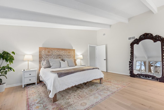 bedroom featuring lofted ceiling with beams, light wood finished floors, visible vents, and baseboards