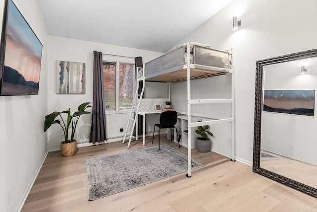 bedroom with vaulted ceiling, baseboards, and wood finished floors