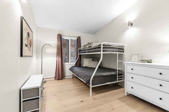 bedroom with lofted ceiling and light wood finished floors