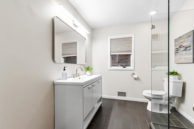 bathroom with visible vents, toilet, baseboards, and wood finished floors