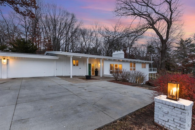 view of front of property featuring concrete driveway, a chimney, and an attached garage