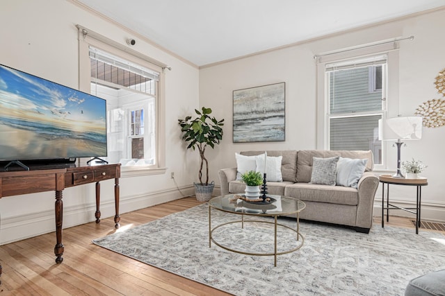 living area featuring baseboards, crown molding, and hardwood / wood-style flooring