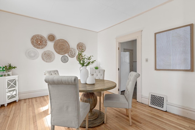 dining space with light wood-type flooring, visible vents, and baseboards