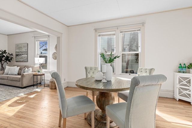 dining area featuring baseboards, a healthy amount of sunlight, light wood-type flooring, and ornamental molding