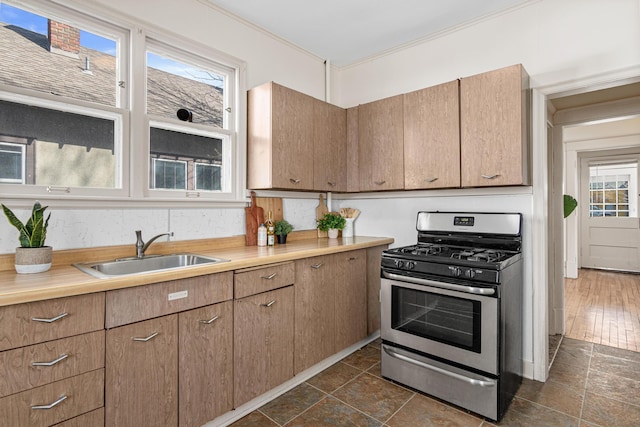 kitchen featuring ornamental molding, gas stove, light countertops, and a sink