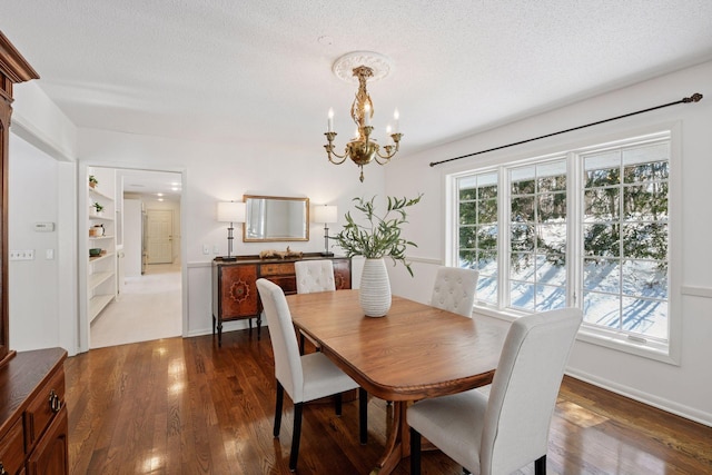 dining area with a textured ceiling, an inviting chandelier, dark wood finished floors, and a healthy amount of sunlight