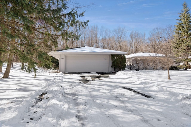 snow covered garage featuring a detached garage