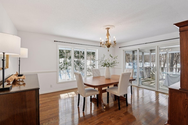 dining area with a chandelier, baseboards, a textured ceiling, and wood finished floors