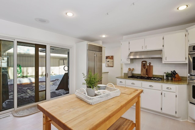 kitchen featuring visible vents, under cabinet range hood, decorative backsplash, white cabinets, and stainless steel appliances