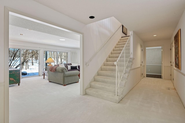 stairway with recessed lighting and carpet floors