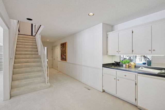 kitchen featuring visible vents, light carpet, a sink, recessed lighting, and white cabinets